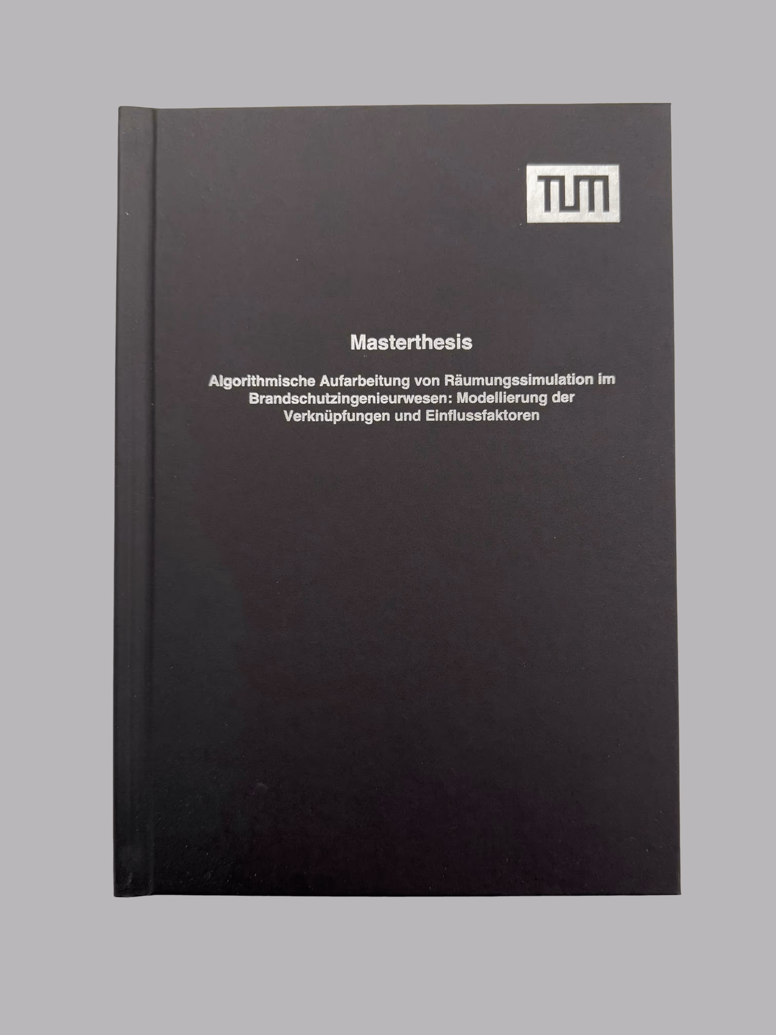 Black hardcover master thesis book with white text in German on fire safety engineering and a TUM logo on the upper right corner.