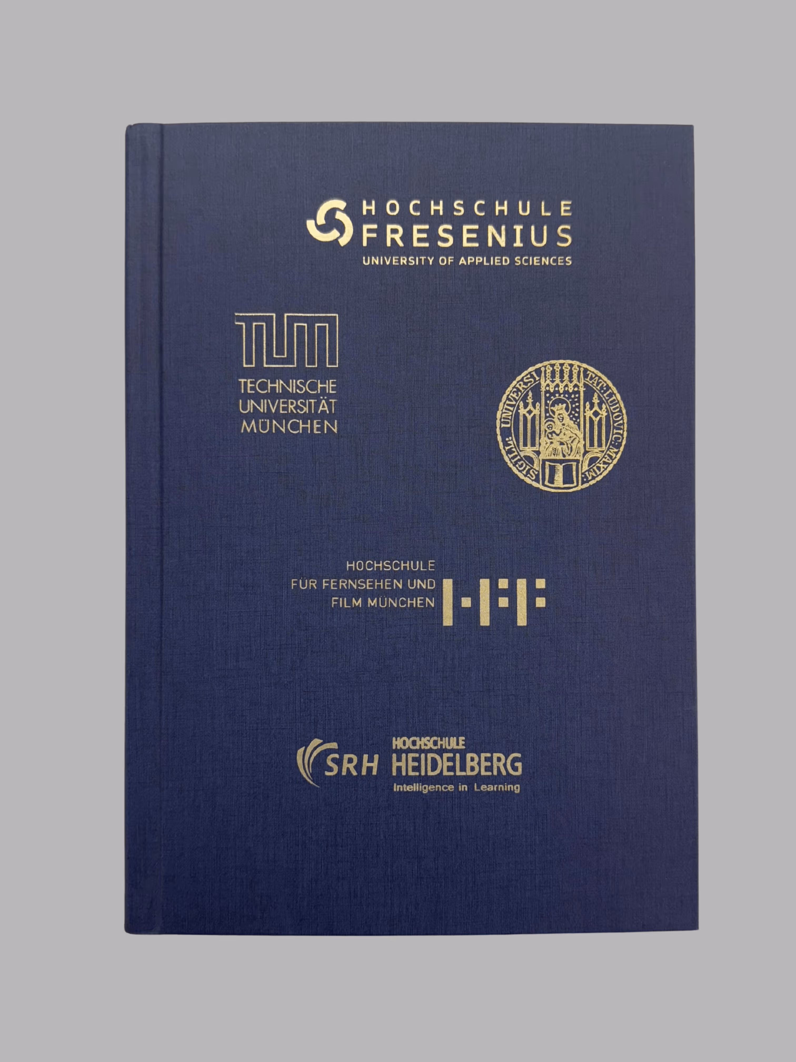 Blue hardcover book with gold logos and names of German universities including Hochschule Fresenius, Technische Universität München, Hochschule für Fernsehen und Film München, and SRH Hochschule Heidelberg.