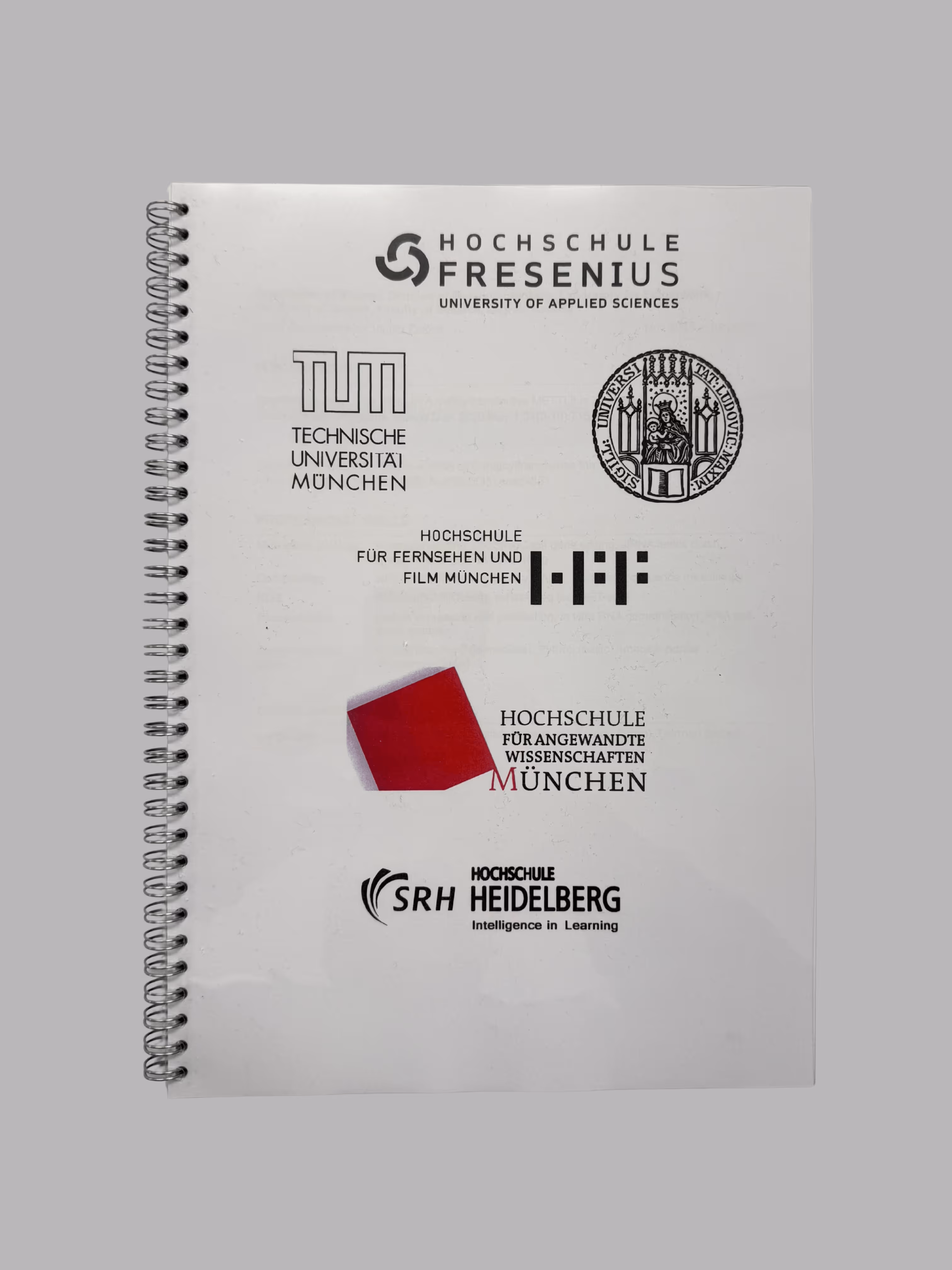 Spiral-bound notebook cover displaying logos and names of German universities including Hochschule Fresenius, Technische Universität München, Hochschule für Fernsehen und Film München, Hochschule für Angewandte Wissenschaften München with a red cube logo, and SRH Hochschule Heidelberg.