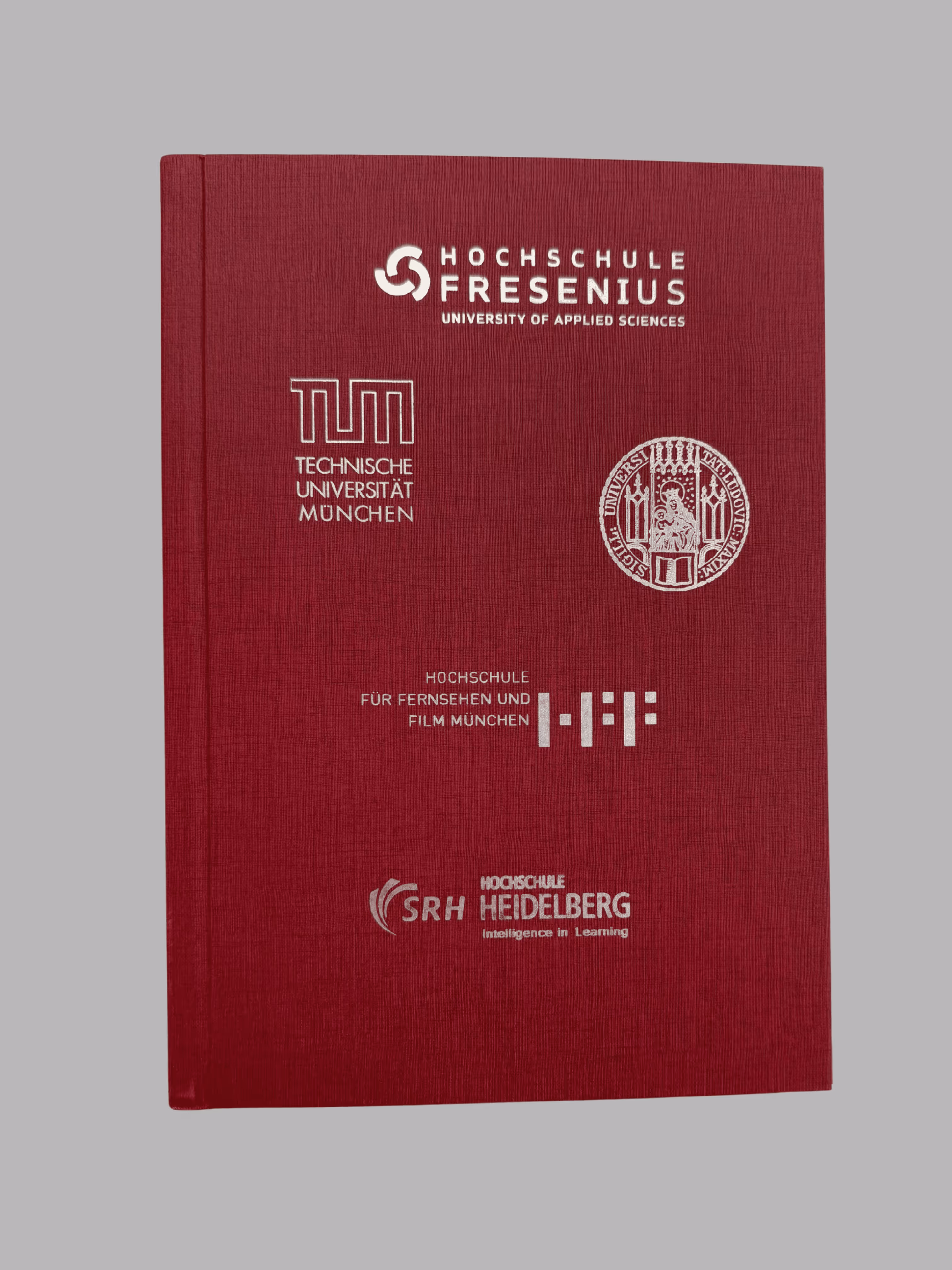 Red hardcover book featuring logos and names of German universities including Hochschule Fresenius, Technische Universität München, Hochschule für Fernsehen und Film München, and SRH Hochschule Heidelberg.